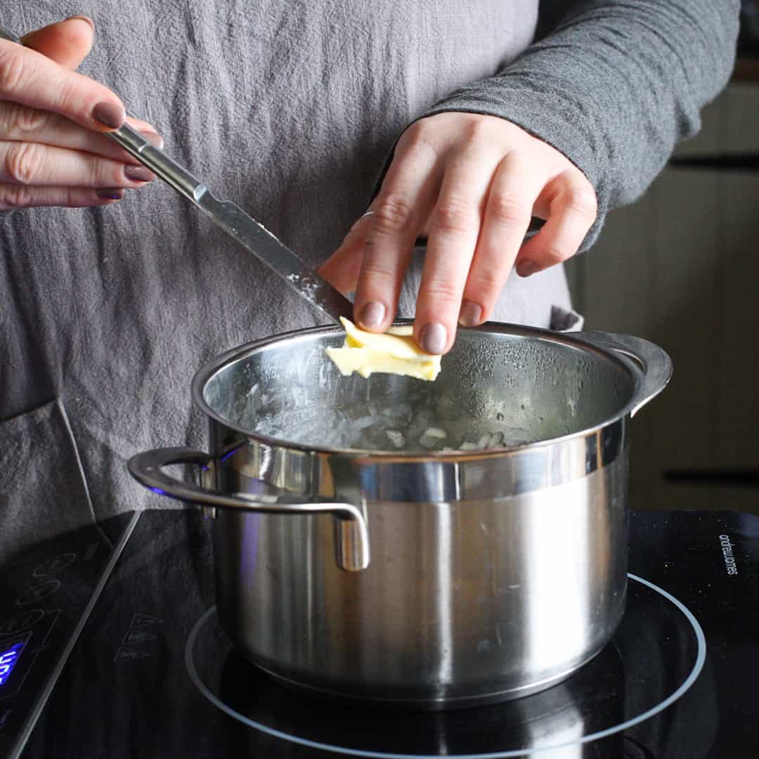 Woman adding butter into a stainless steel saucepan