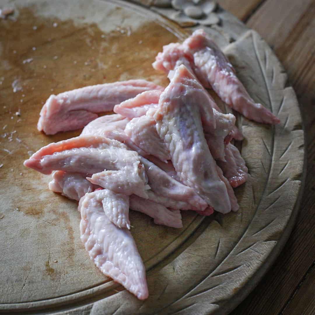 Small pile of chicken wing tips on a wooden chopping board