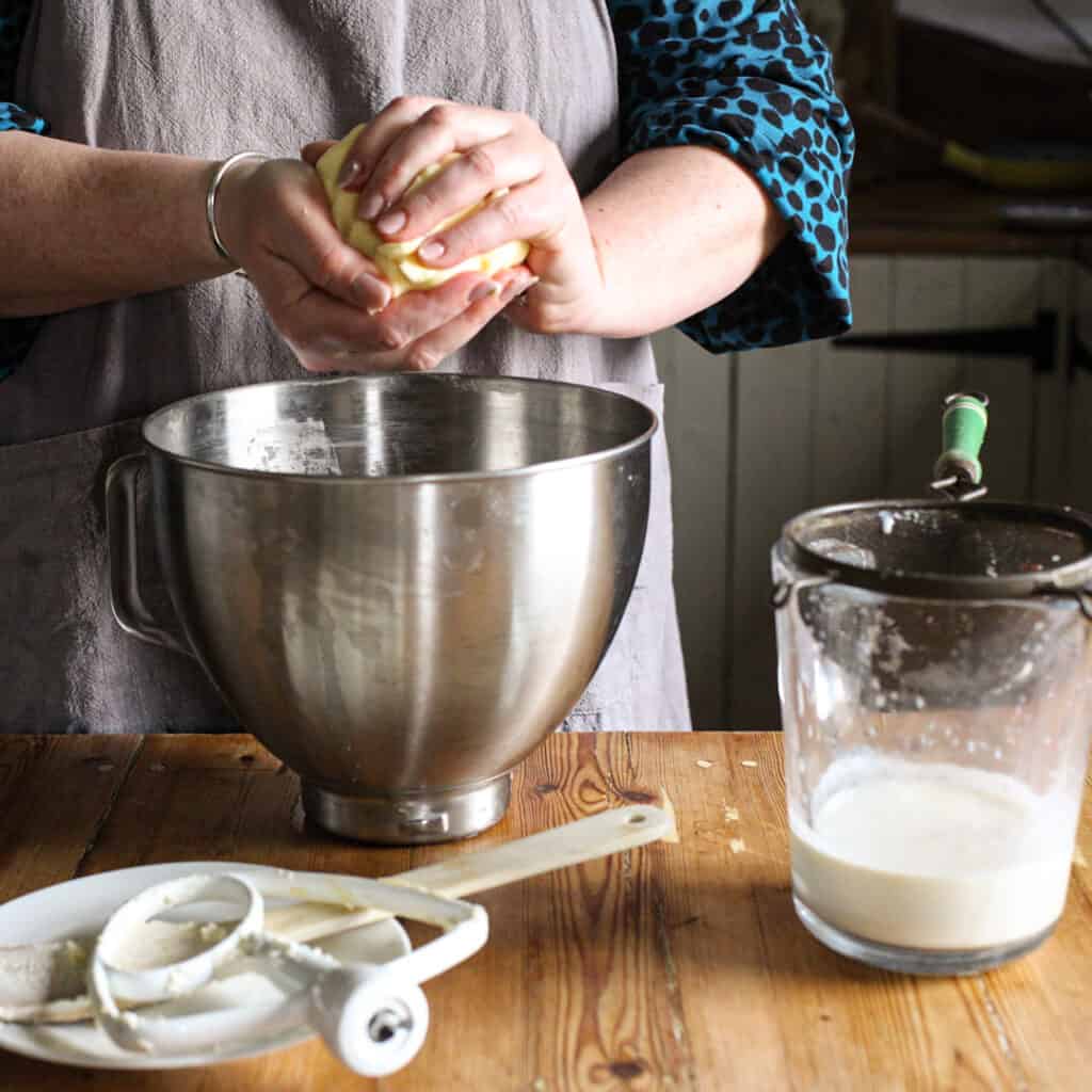 Woman squashing a lump of freshly made butter in her hands to remove the buttermilk
