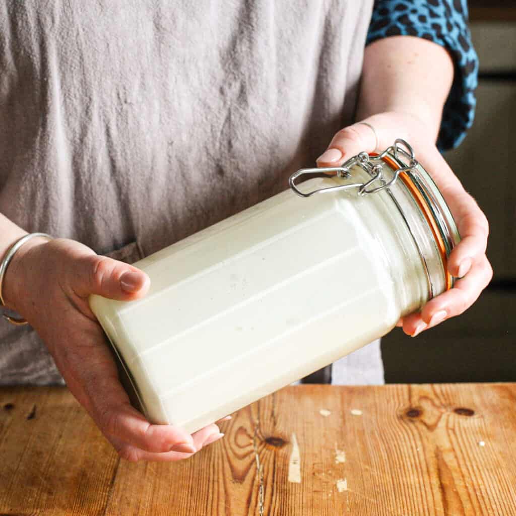 Woman shaking a glass jar filled with cream to make butter