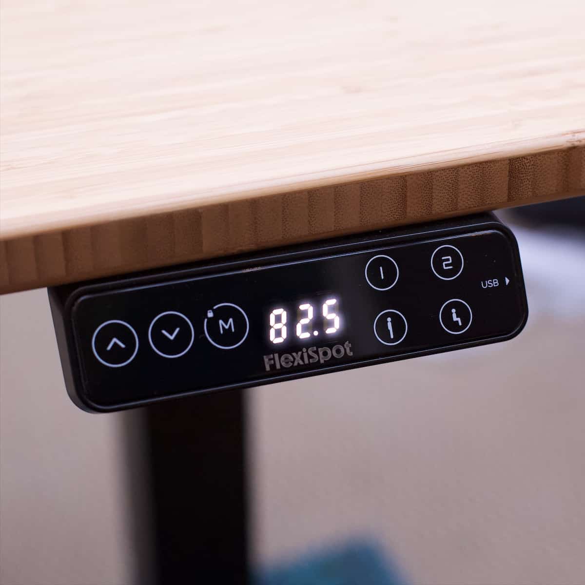 A black digital touchpad used to adjust the height of a standing desk