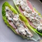 Two Large green lettuce leaves on a grey plate loaded with creamy ham filling
